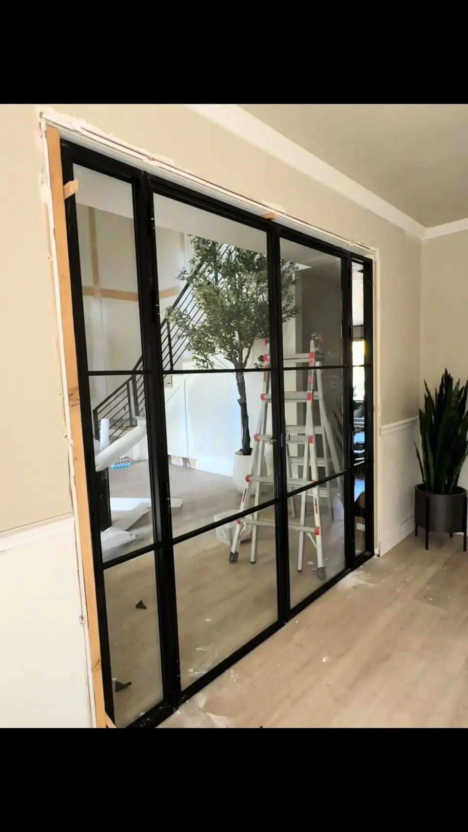 Black-frame multi-panel glass doors installed in an interior opening during a remodel